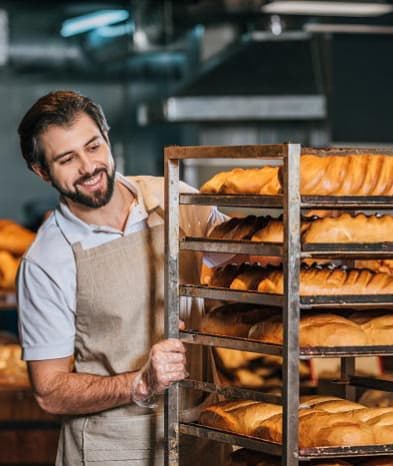 Baker man looking at loaves with a smile